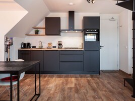 Uma cozinha moderna com armários escuros, forno embutido e máquina de café.