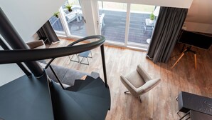 A modern living room with a staircase, a view of the outdoor patio, and a large window. - Apartment Located Directly on the Sneekermeer (Offingawier)
