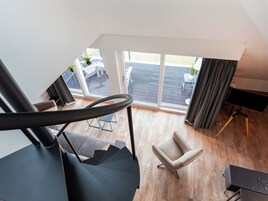 Uma sala de estar moderna com escada, vista para o pátio externo e uma janela grande.