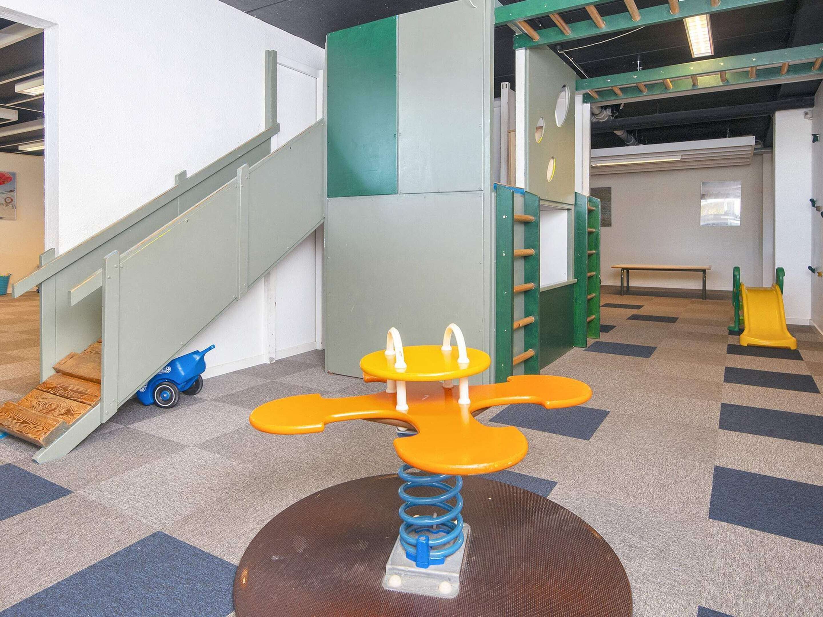 A children's play area with a seesaw, a climbing wall, and a slide.