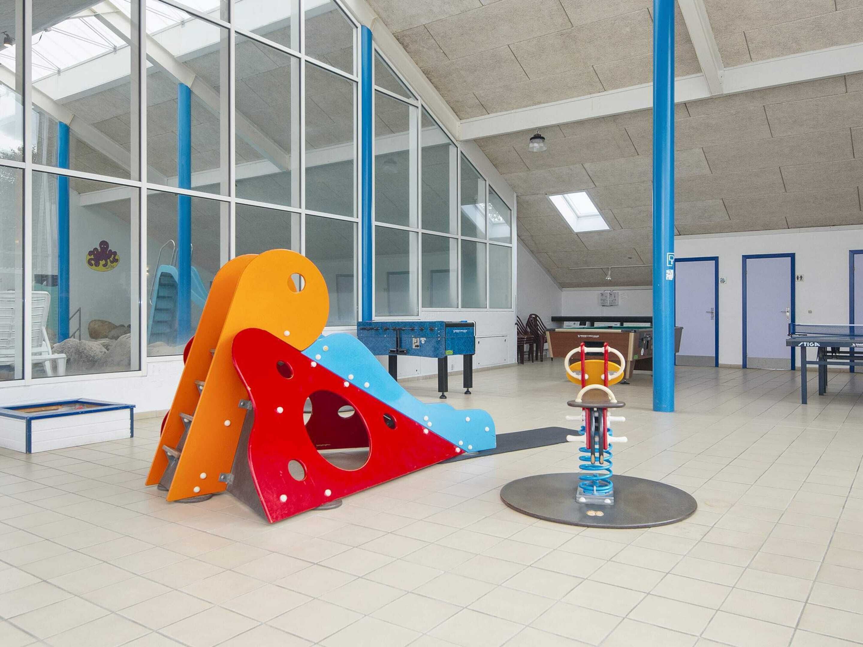 A spacious indoor play area with a climbing structure, a ping pong table, and a small seating area.