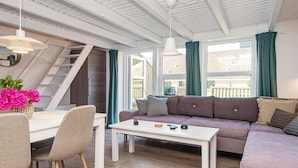 Una sala de estar moderna con un sofá, una mesa de comedor con sillas y una escalera.