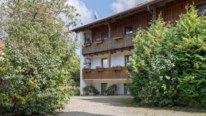 A traditional chalet with wooden balconies, a paved courtyard, and lush greenery. - Farmhouse in Neukirchen Near Heiligen Blut (Neukirchen Beim Heiligen Blut)