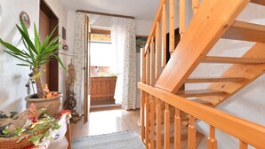 A wooden staircase leading to an upper floor, a potted plant, and a doorway to a balcony with a view. - Farmhouse in Neukirchen Near Heiligen Blut (Neukirchen Beim Heiligen Blut)