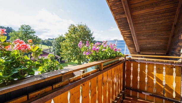A wooden balcony with a view of a garden and solar panels in the background. - Farmhouse in Neukirchen Near Heiligen Blut (Neukirchen Beim Heiligen Blut)
