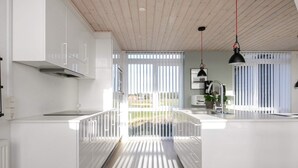 Een moderne keuken met witte kasten, een houten plafond en een groot kookeiland met een spoelbak.