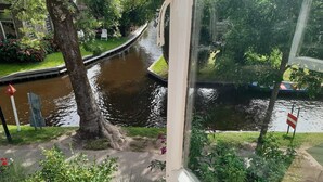 A view of a canal with a bridge, surrounded by greenery and a flag. - Lodge in Giethoorn With Breakfast (Giethoorn)