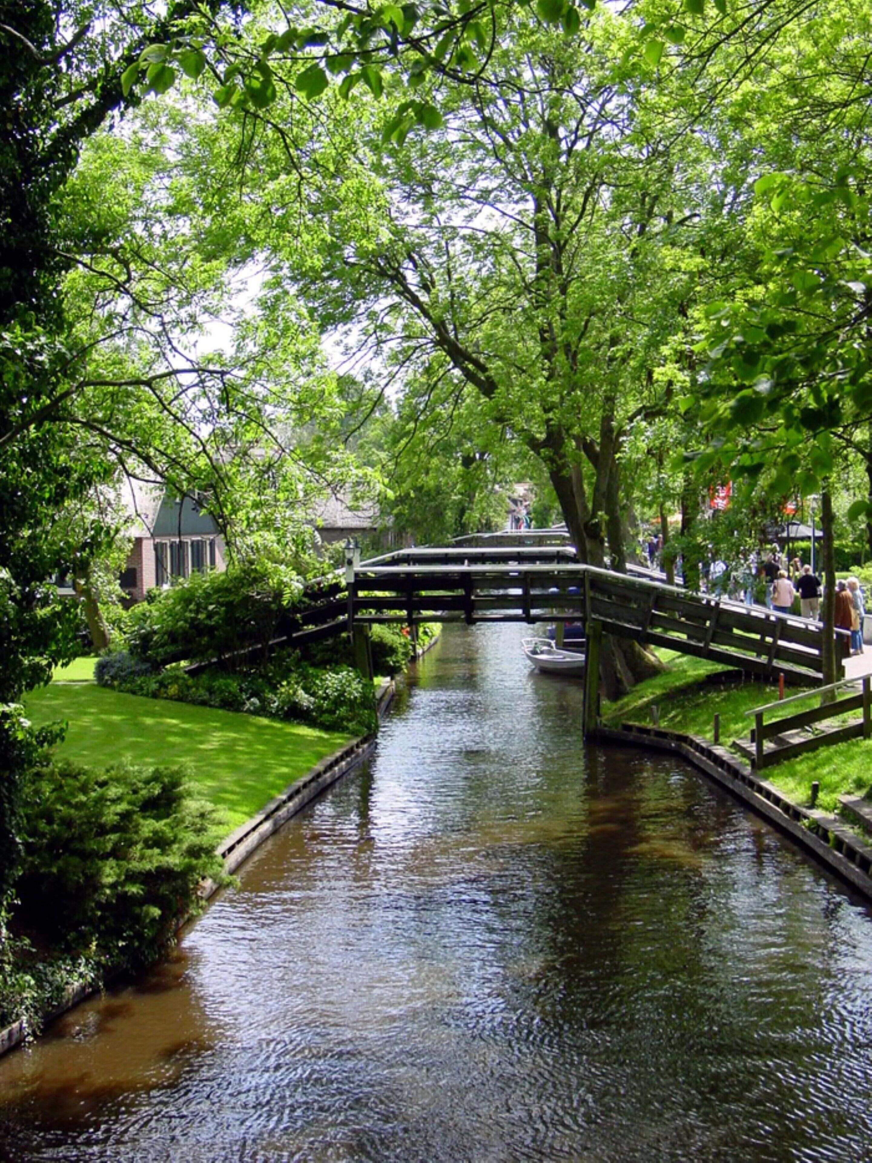 A canal with a wooden bridge and a boat.