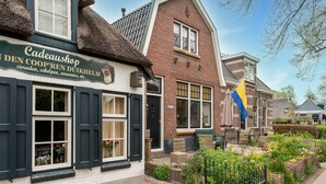 A traditional building with a sign for 'Cadeaushop' and a flag. - Lodge in Giethoorn With Breakfast (Giethoorn)