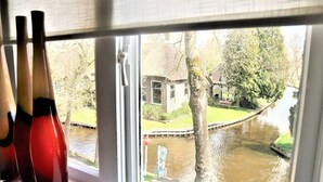 A window view of a canal with a house and trees. - Lodge in Giethoorn With Breakfast (Giethoorn)