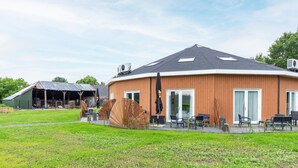 A modern building with a curved roof, large windows, and outdoor seating. - Attractive Holiday Home in Gorp and Roovert Estate (Goirle)
