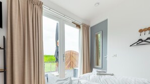 A hotel room with two beds, a large window with curtains, a wooden deck visible through the window, and a mirror on the wall. - Attractive Holiday Home in Gorp and Roovert Estate (Goirle)