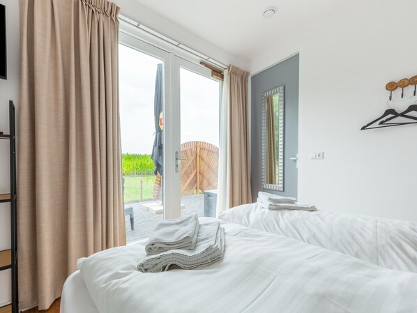 A hotel room with two beds, a large window with curtains, a wooden deck visible through the window, and a mirror on the wall. - Attractive Holiday Home in Gorp and Roovert Estate (Goirle)