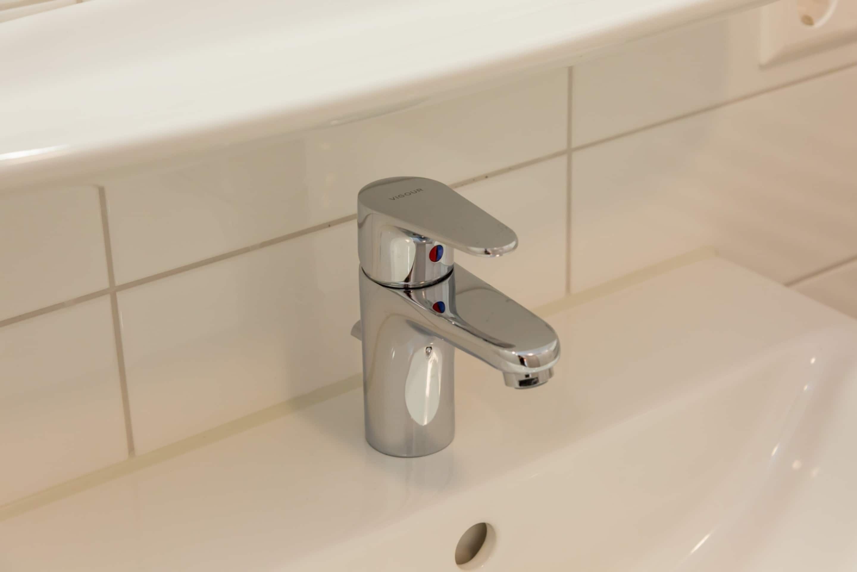 Een wastafel met een chromen kraan en een afvoer met één gat.