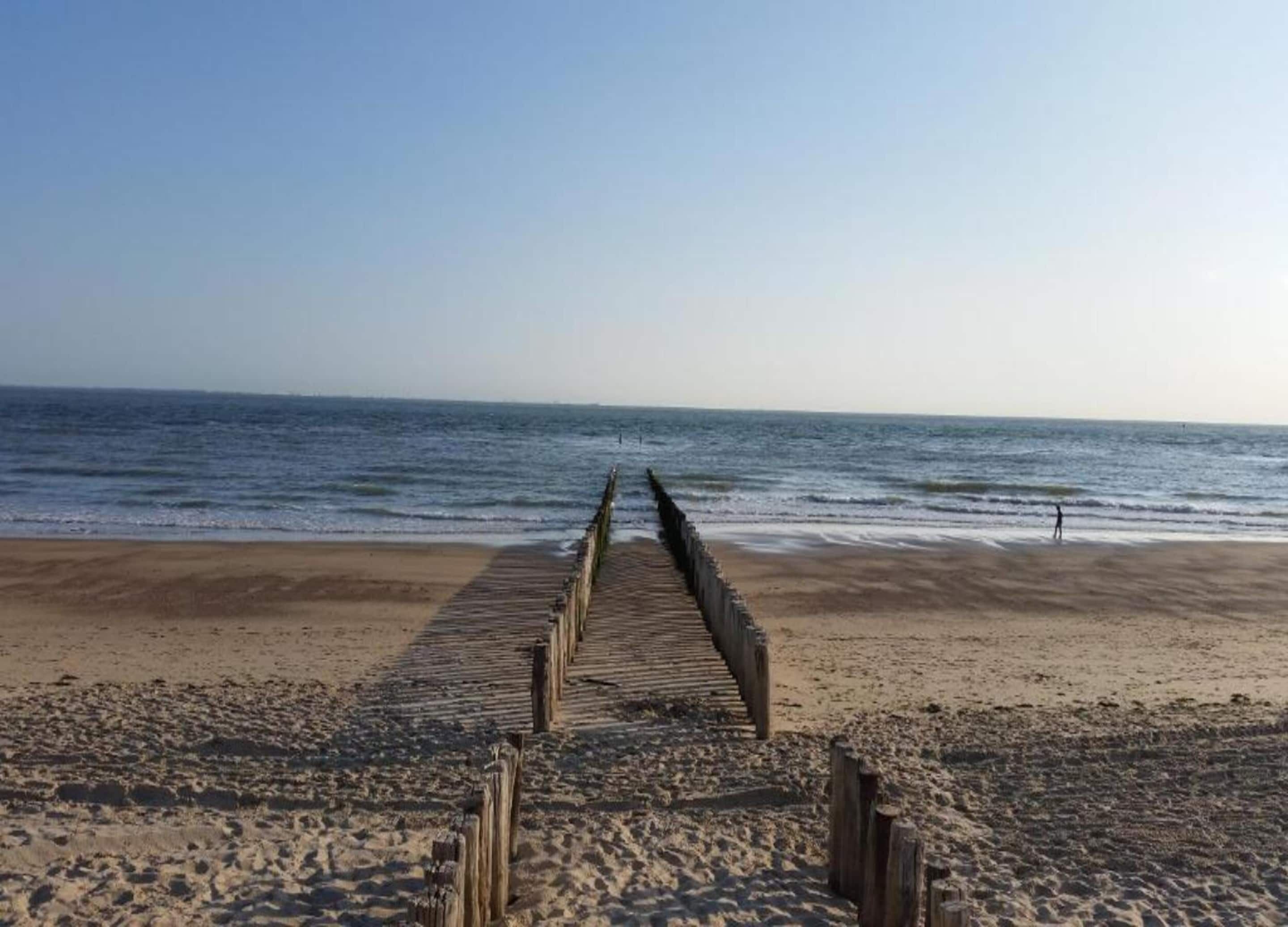 En strand med en træpromenade, der fører ned til vandet.