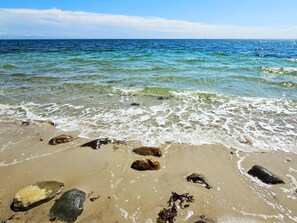 A beach with clear water, rocks, and a distant lighthouse. - 4 Person Holiday Home in Sydals (Sydals)