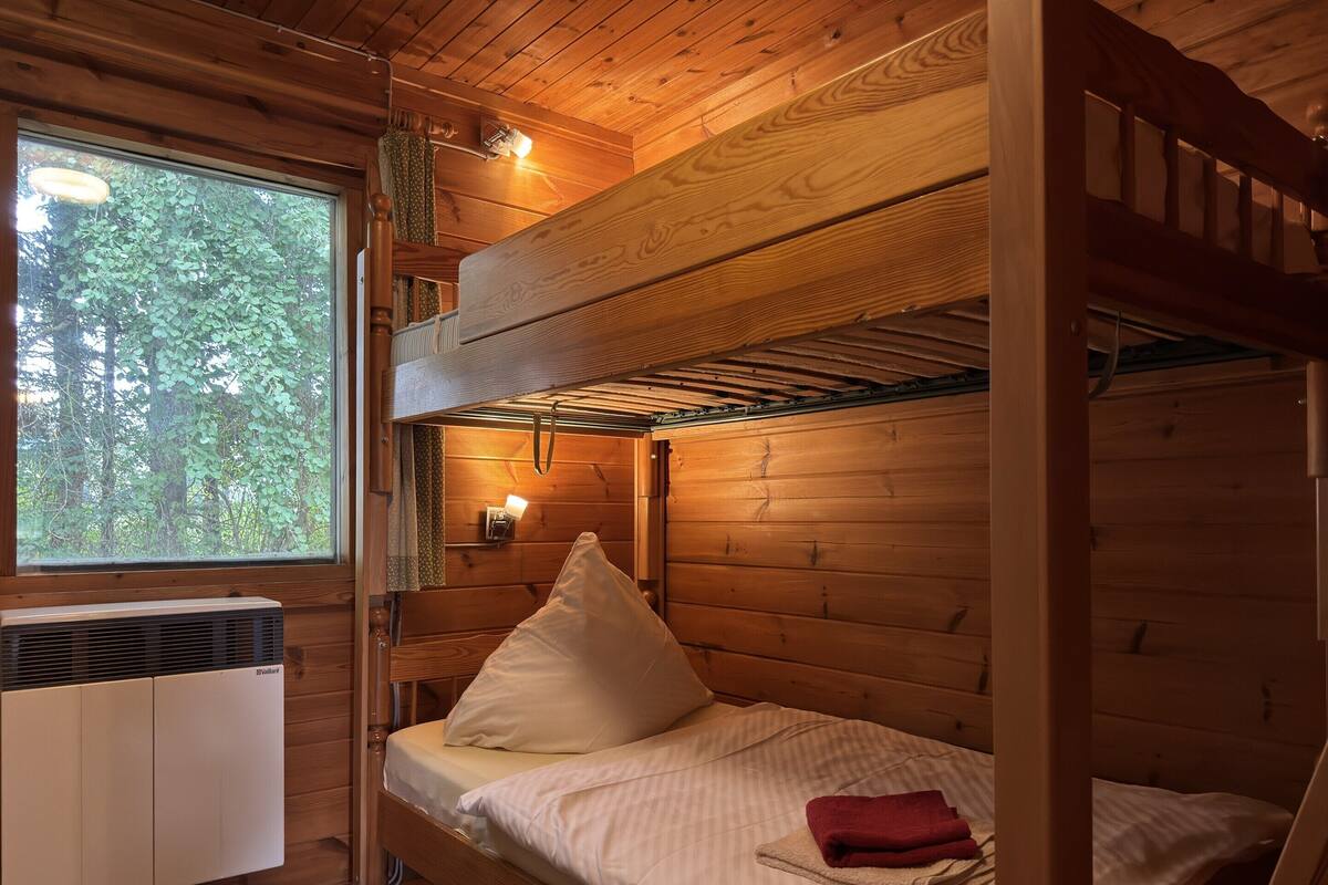 Camera con letto a castello, finestra e un asciugamano rosso sul letto, oltre a un termosifone a parete.
