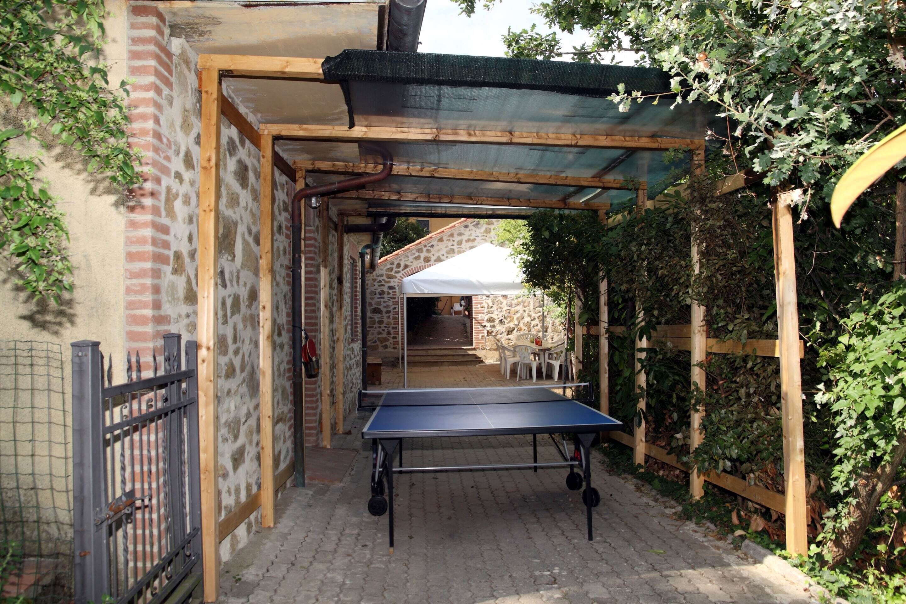 A ping pong table in a covered outdoor area with brick walls and a stone structure in the background.