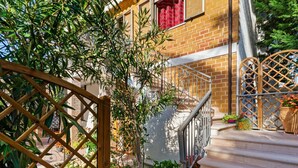 A staircase leading to a brick building with a wooden gate and potted plants. - Pleasant Apartment With Courtyard (Saludecio)
