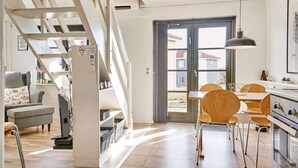 Eine moderne Küche mit Essbereich, Holzstühlen und einer Treppe, die zu einem Schlafgeschoss führt.