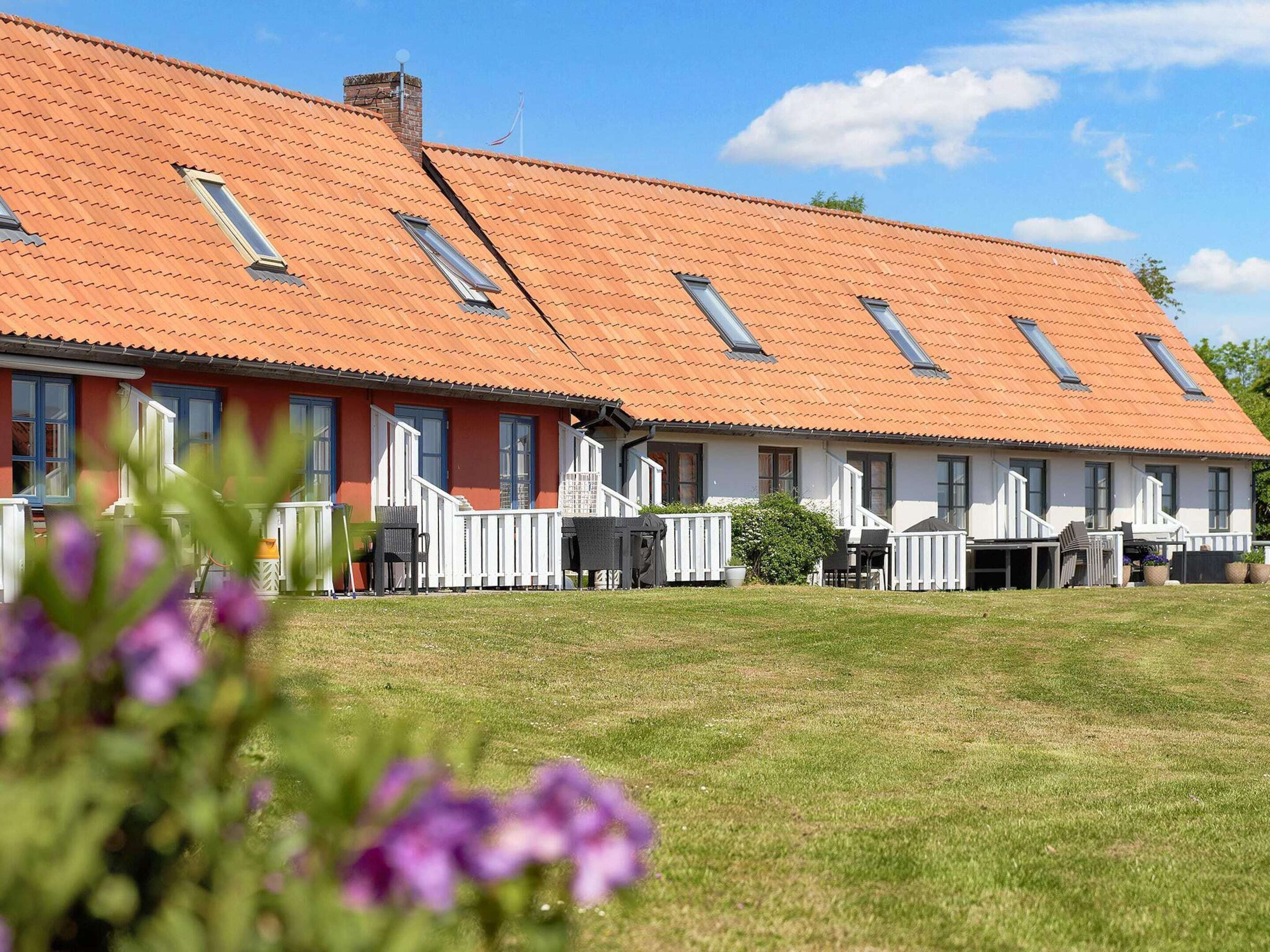 A row of single-story buildings with red-tiled roofs and multiple windows.