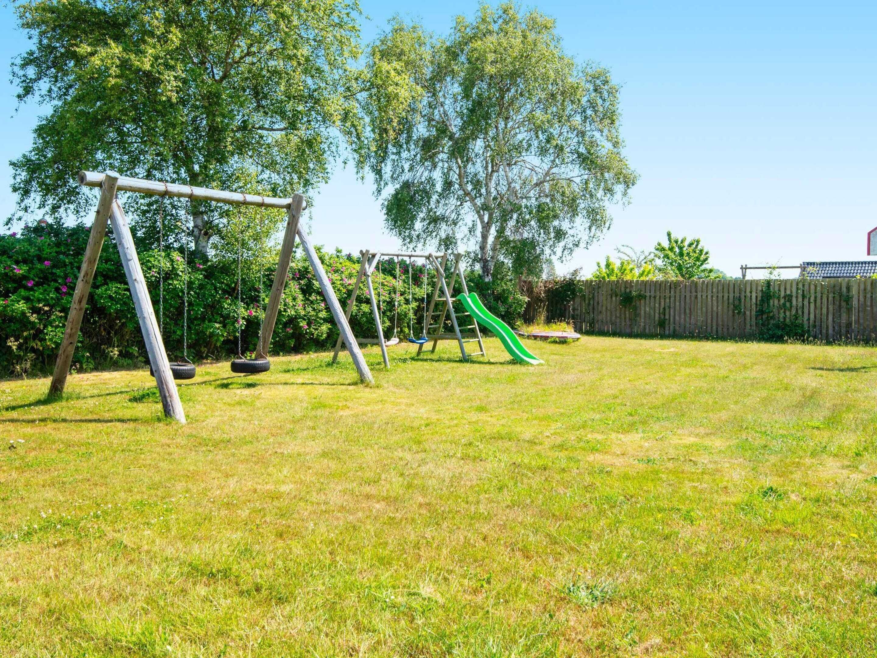 A backyard with a swing set, a tire swing, and a slide.