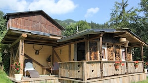 A rustic wooden cabin with a porch, a chair, and potted plants. - Luxurious Apartment in Fugen Near Forest (Fuegenberg)
