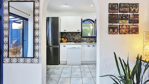 A modern kitchen with white cabinets, a stainless steel refrigerator, and a dishwasher. There is a decorative mirror with a black frame and a small window above the sink. - CASA MAY , LUXURY VILLA

 UNIQUE ONE OFF MOROCCAN VILLA

5 STARS  on Tripadvisor (Corralejo)