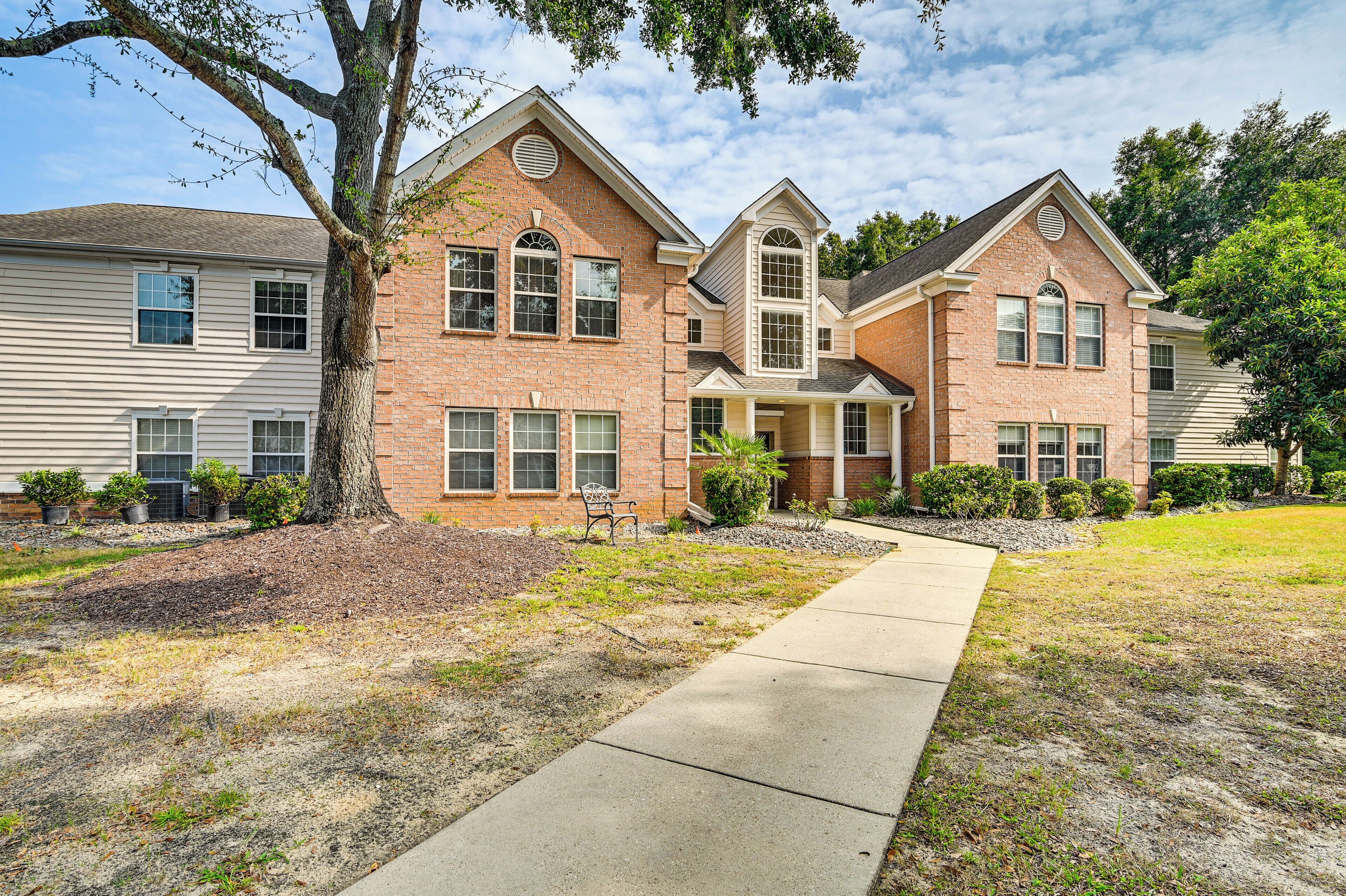 A two-story brick house with a front porch, a driveway, and a well-maintained lawn.