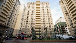 A high-rise residential building with multiple balconies and a playground area in the foreground. - Kristal Absheron (Baku)