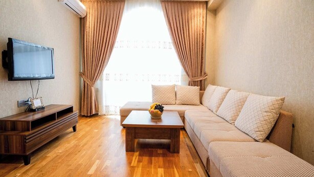 A modern living room with a wooden floor, a sofa, a coffee table, and a flat-screen TV. - Kristal Absheron (Baku)
