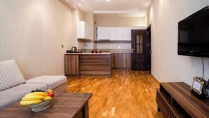 A modern apartment with a kitchen, a dining area with a fruit basket, and a TV. - Kristal Absheron (Baku)