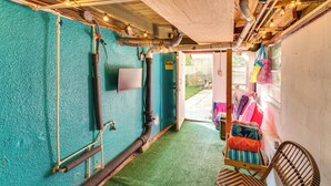 A room with teal walls, exposed pipes, and a wooden ceiling. There is a chair and a window with a view of the outside. - Daytona Beach Studio: Walk to Boardwalk + Pier! (Daytona Beach)