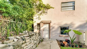 A stone wall, a door, and potted plants in front of a building. - Daytona Beach Studio: Walk to Boardwalk + Pier! (Daytona Beach)