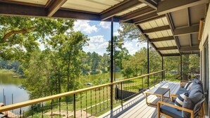 Une terrasse couverte avec des sièges extérieurs et une vue sur un lac et des arbres.