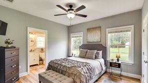 A bedroom with a bed, a ceiling fan, a nightstand, a bench, and a window with a view of the outdoors. - Georgia Countryside Home: 3 Mi to Wild Adventures! (Valdosta)