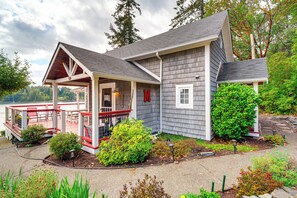 A two-story house with a covered porch, a deck, and a view of a lake.