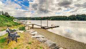 A lakeside view with a bench, dock, and rocky shoreline. - Bayfront Home w/ Private Beach in Vaughn! (Vaughn)