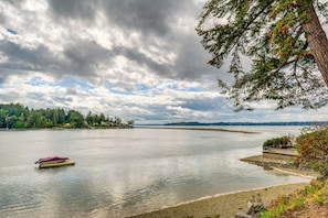 A calm lake with a small boat on the water, surrounded by trees and a cloudy sky.