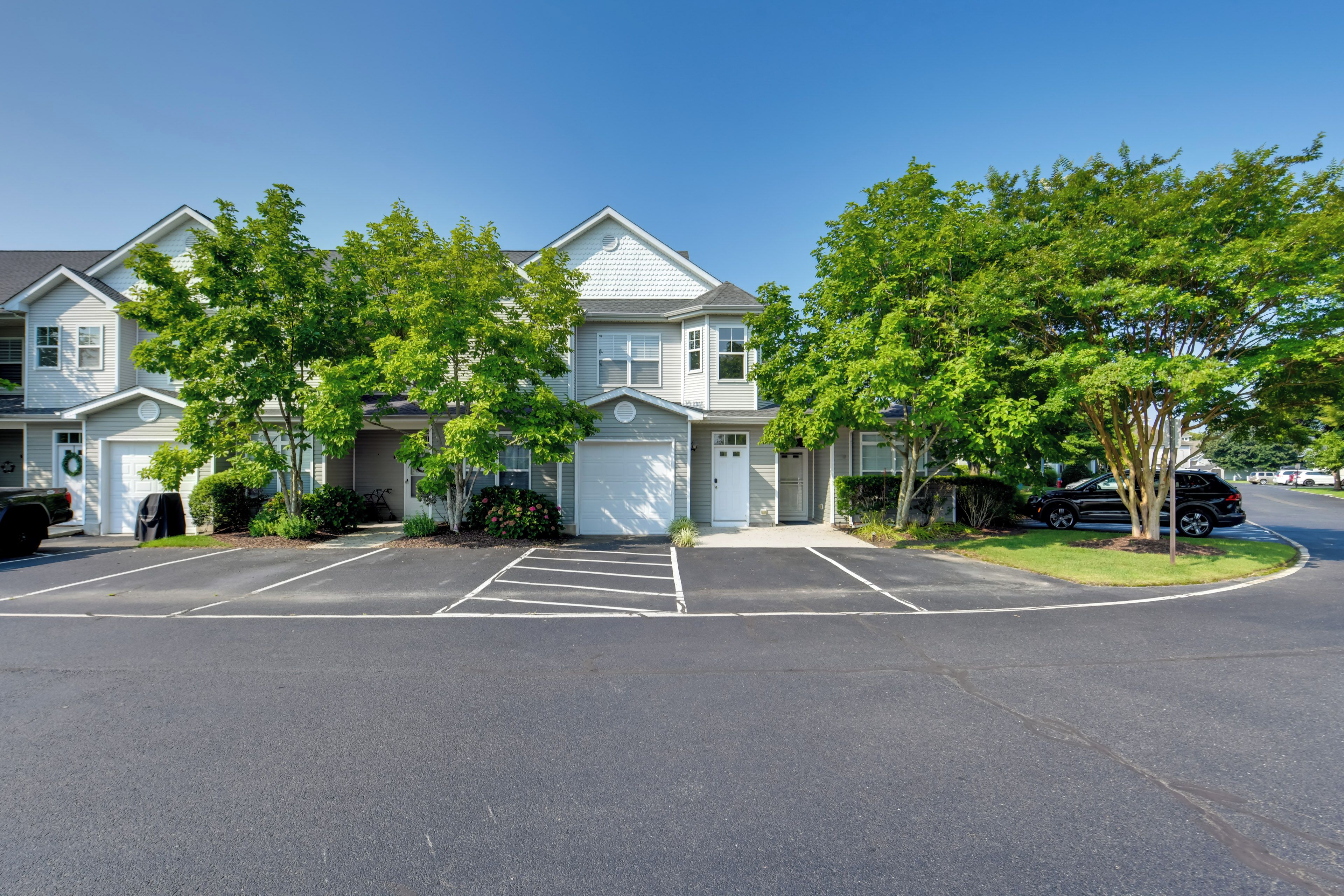 A residential area with two-story houses, a parking lot, and a clear blue sky.
