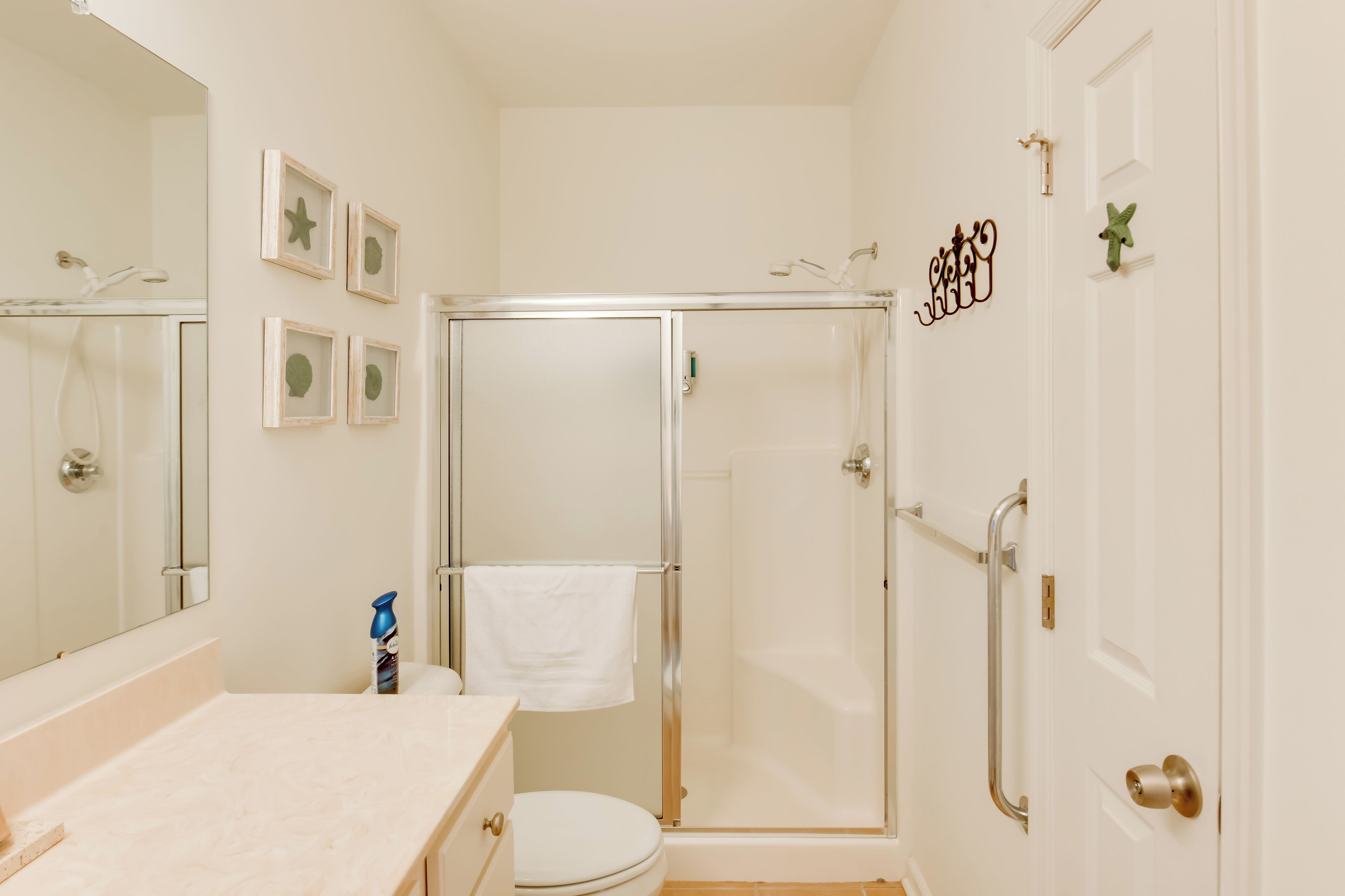 Een badkamer met een douchecabine van glas, een wit toilet en een wastafel met een handdoek aan de muur.