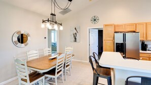 A modern kitchen with wooden cabinets, a stainless steel refrigerator, and a dining area with a wooden table and white chairs. - 4 Mi to Beach: Lewes Townhome w/ Ping-pong Table (Rehoboth Beach)
