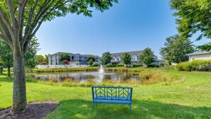 A park with a pond, a bench, and a building in the background. - 4 Mi to Beach: Lewes Townhome w/ Ping-pong Table (Rehoboth Beach)