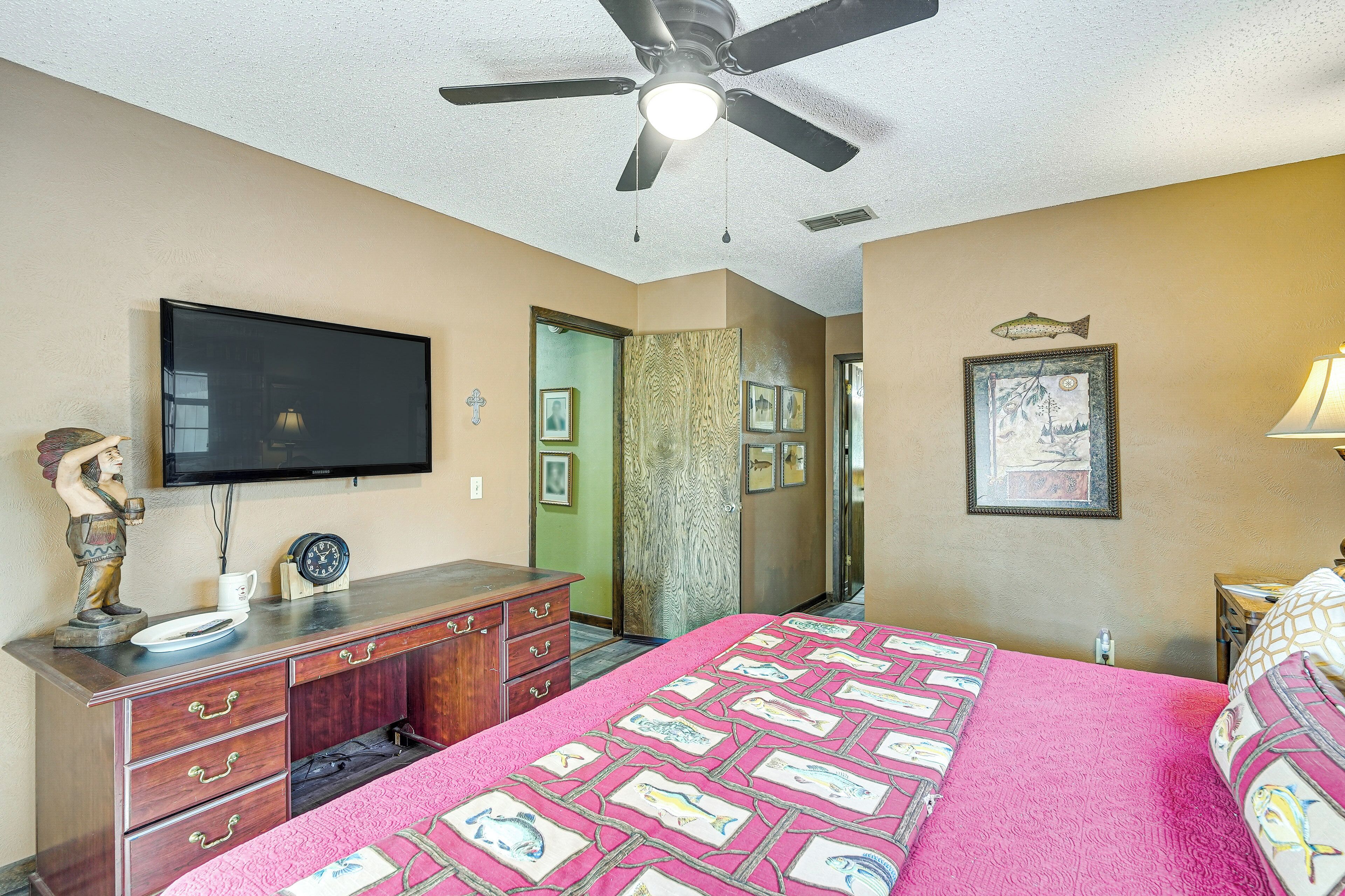 A bedroom with a bed, a dresser, a television, and a ceiling fan.