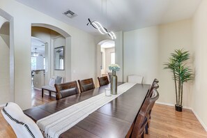 Enjoy meals with friends and family in this spacious dining area, featuring a long table and six comfortable chairs.