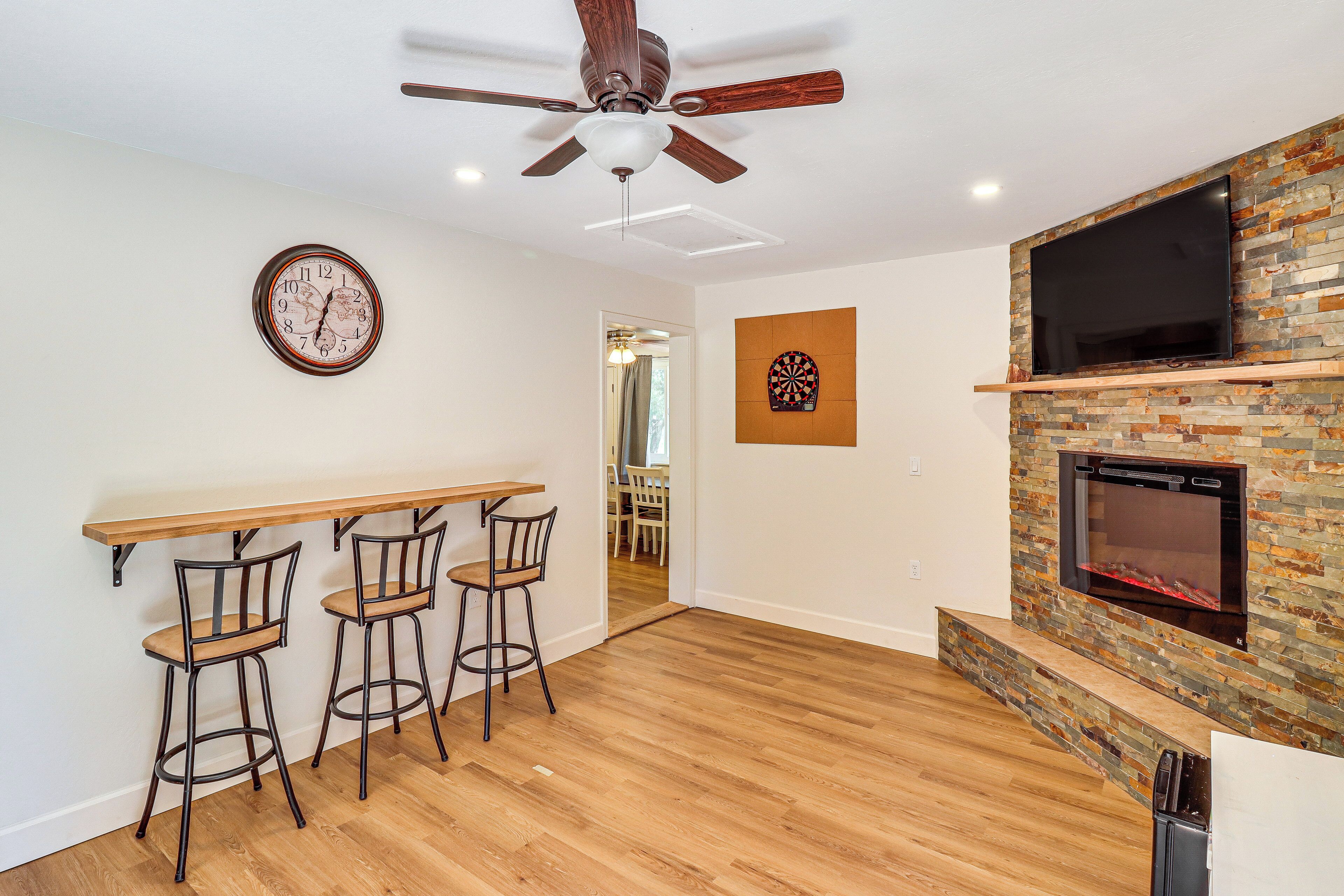 A modern kitchen with a wooden bar, a built-in TV, and a stone fireplace.