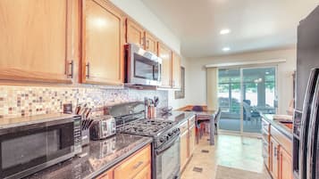 A kitchen with wooden cabinets, a microwave, stove, and a refrigerator.