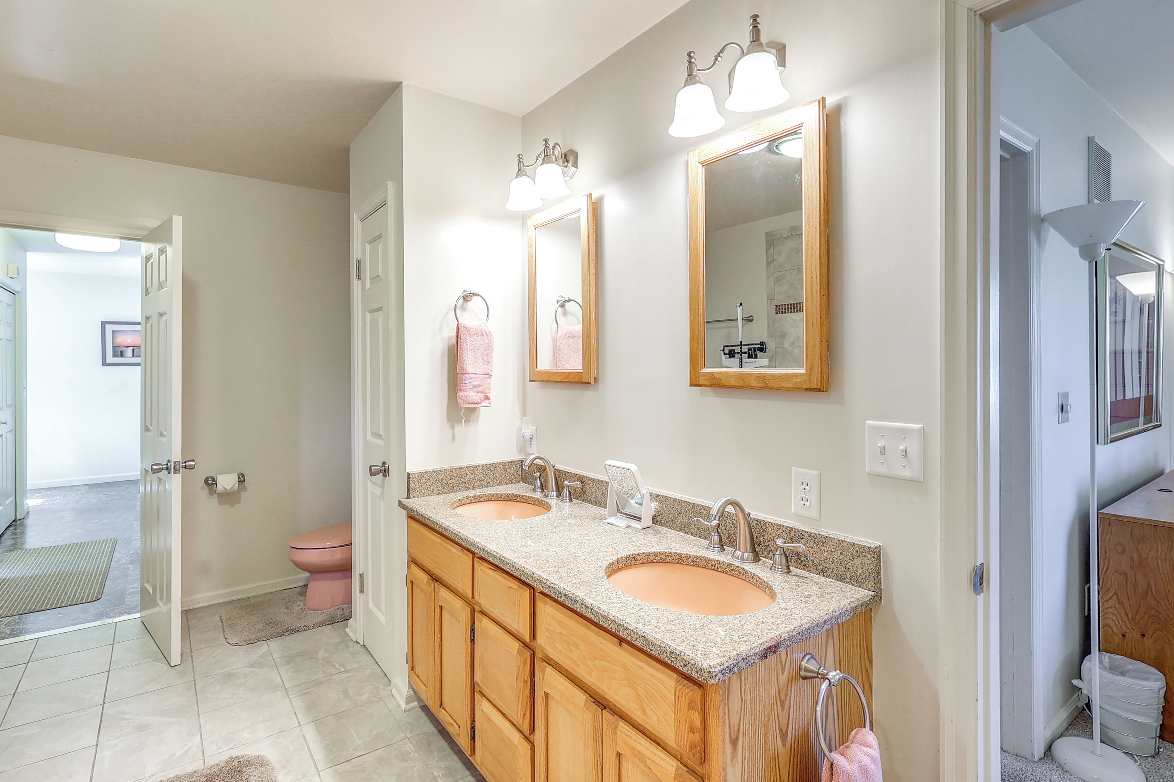 A bathroom with two sinks, wooden cabinets, a toilet, and a shower.