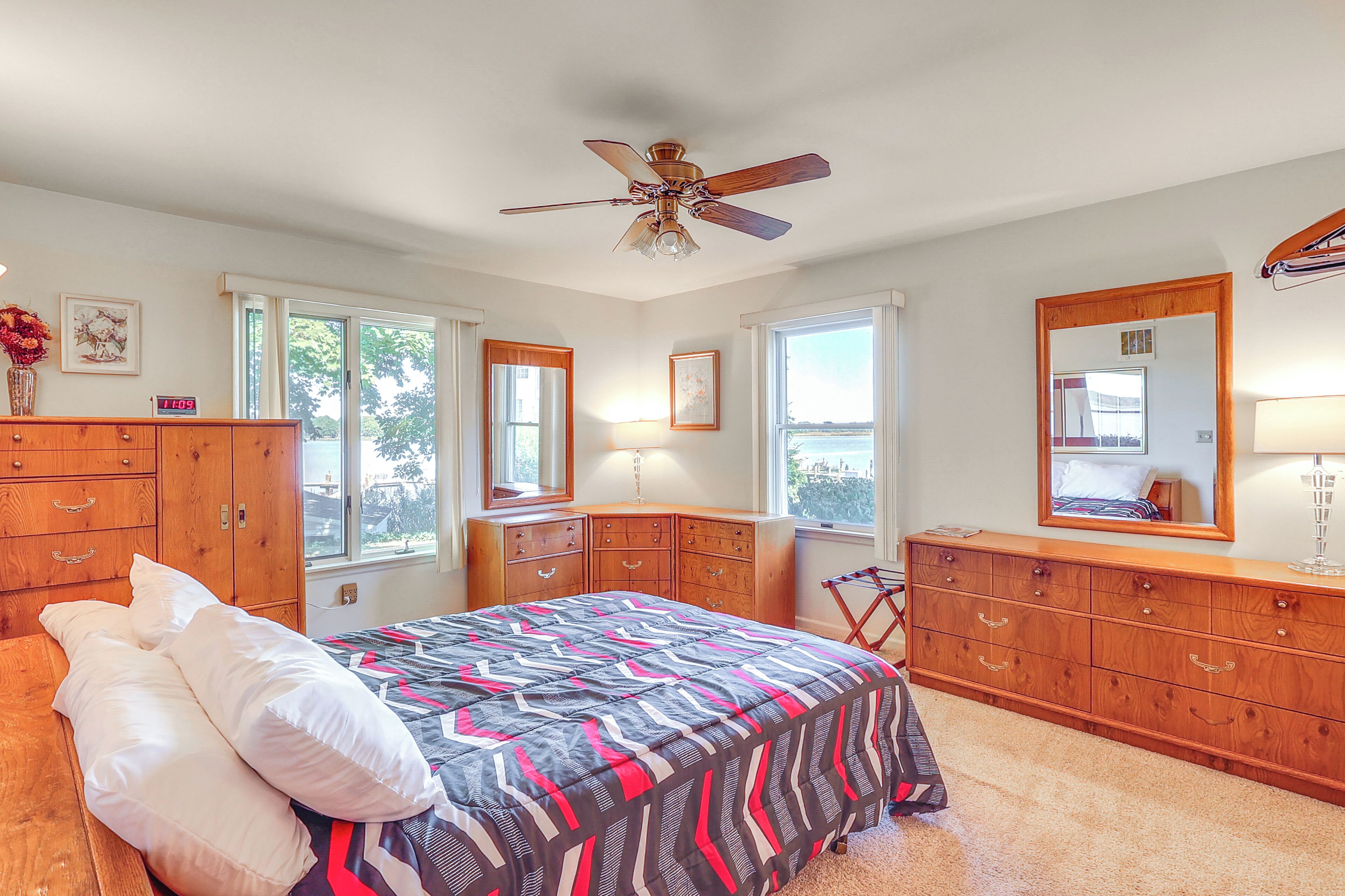 A bedroom with a bed, wooden dresser, and a ceiling fan.
