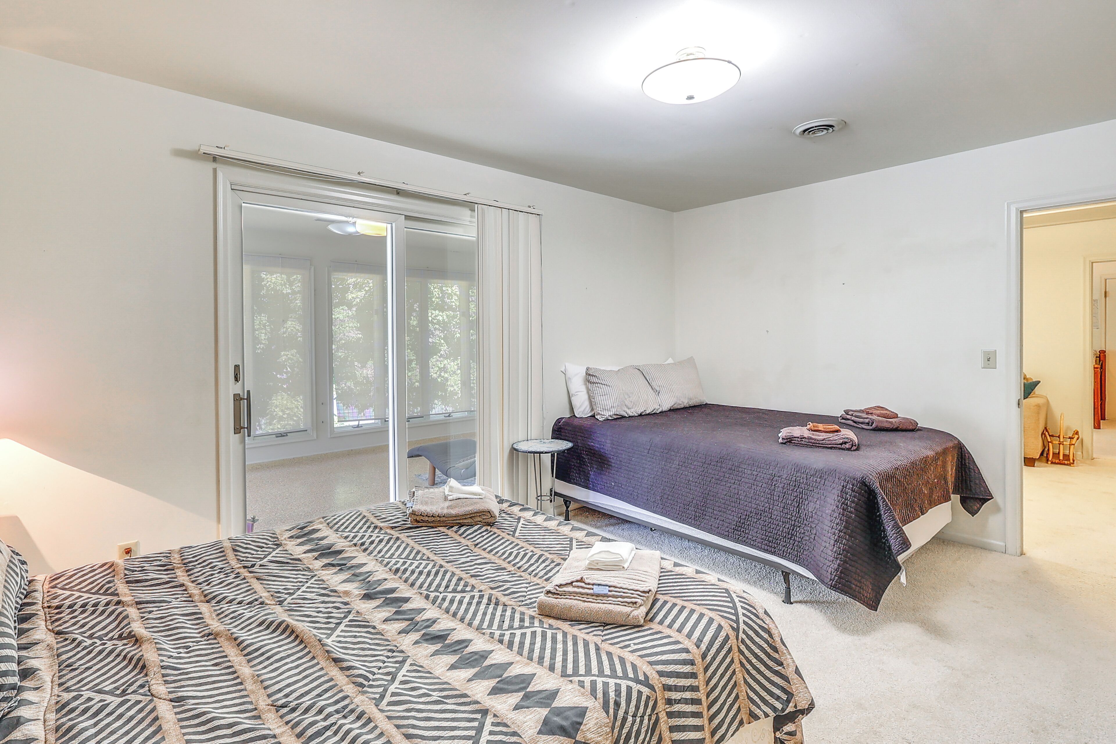 A bedroom with a bed, a bedside table, a window, and a door.